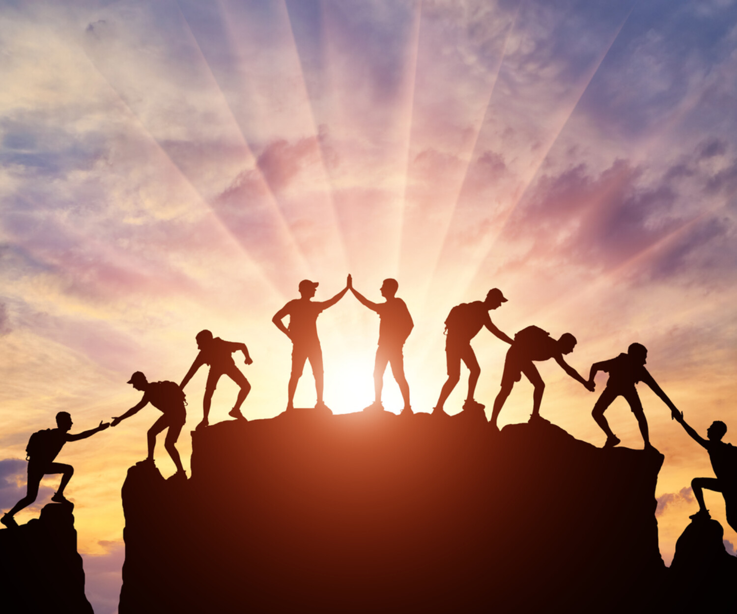 Silhouette of climbers who climbed to the top of the mountain thanks to mutual assistance and teamwork. Conceptual scene of a team of alpinists